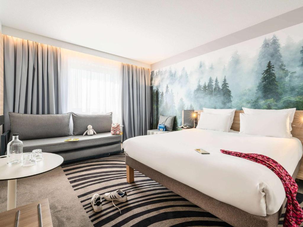 ノワジー・ル・グランにあるNovotel Marne-la-Vallée Noisy-le-Grandの大きなベッドとソファが備わるホテルルームです。