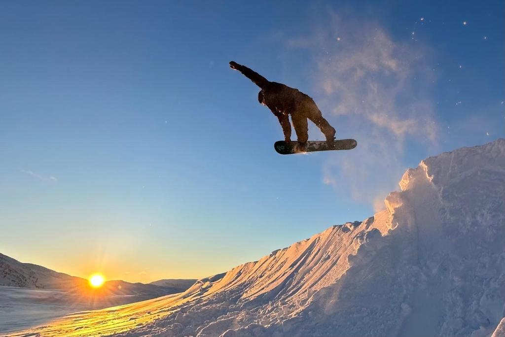 a man flying through the air while riding a snowboard at Tommen’s Crib in Hemsedal