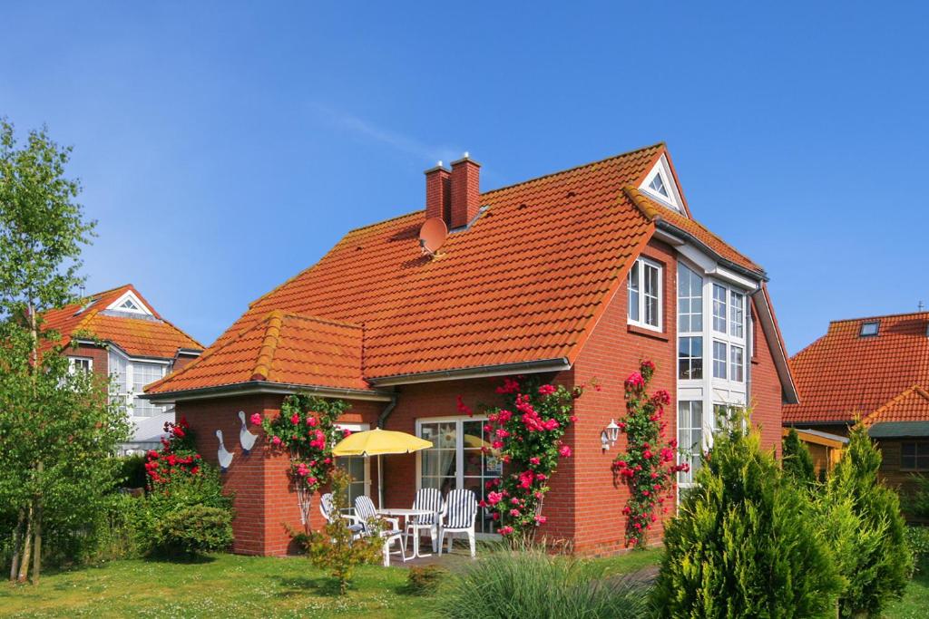 uma casa de tijolos vermelhos com flores em Ferienhaus Dat Krebs Huus em Dornumersiel