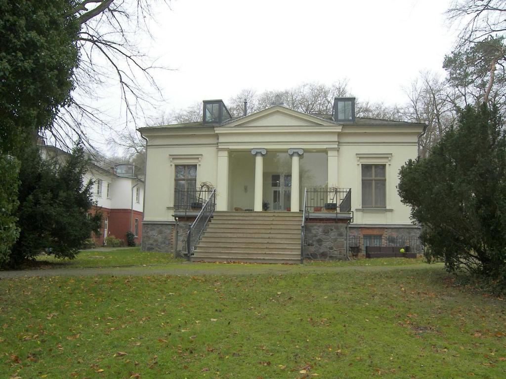 Cette grande maison blanche dispose d'une terrasse couverte et d'escaliers. dans l'établissement Tarnowskis Villa Seeblick, nur 50m zum Strand, WLAN inkl, à Neuhof