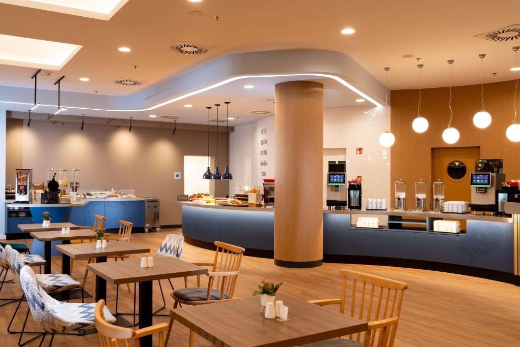 a restaurant with tables and chairs and a counter at Hampton By Hilton Budapest City Centre in Budapest