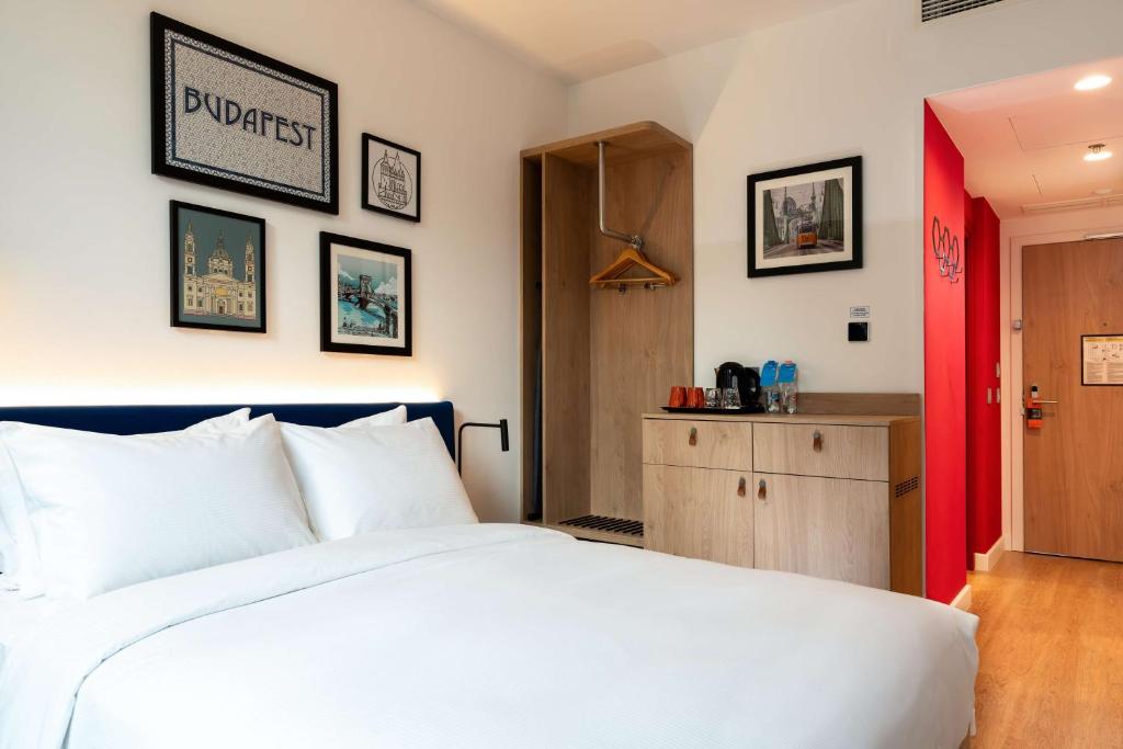 a bedroom with a white bed and a red door at Hampton By Hilton Budapest City Centre in Budapest