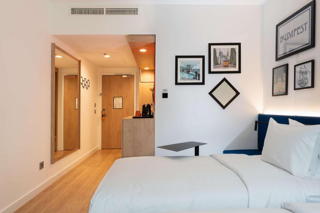 a bedroom with a white bed with a table on it at Hampton By Hilton Budapest City Centre in Budapest