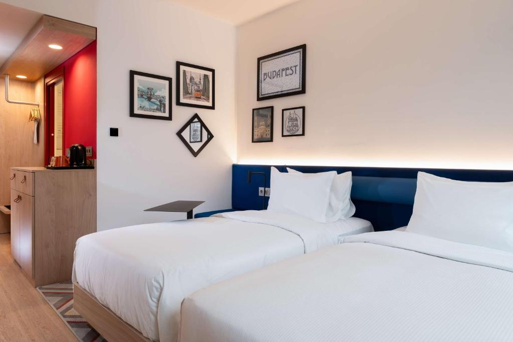 two beds in a hotel room with white sheets at Hampton By Hilton Budapest City Centre in Budapest