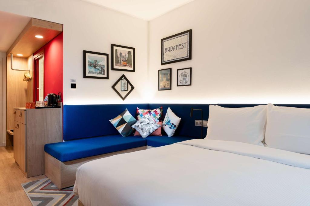 a hotel room with a bed and a blue couch at Hampton By Hilton Budapest City Centre in Budapest