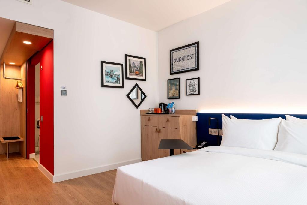 a bedroom with a white bed and some pictures on the wall at Hampton By Hilton Budapest City Centre in Budapest