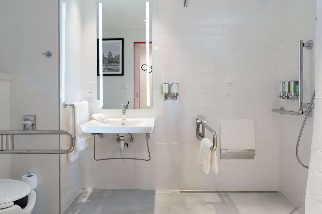 a white bathroom with a sink and a toilet at Hampton By Hilton Budapest City Centre in Budapest