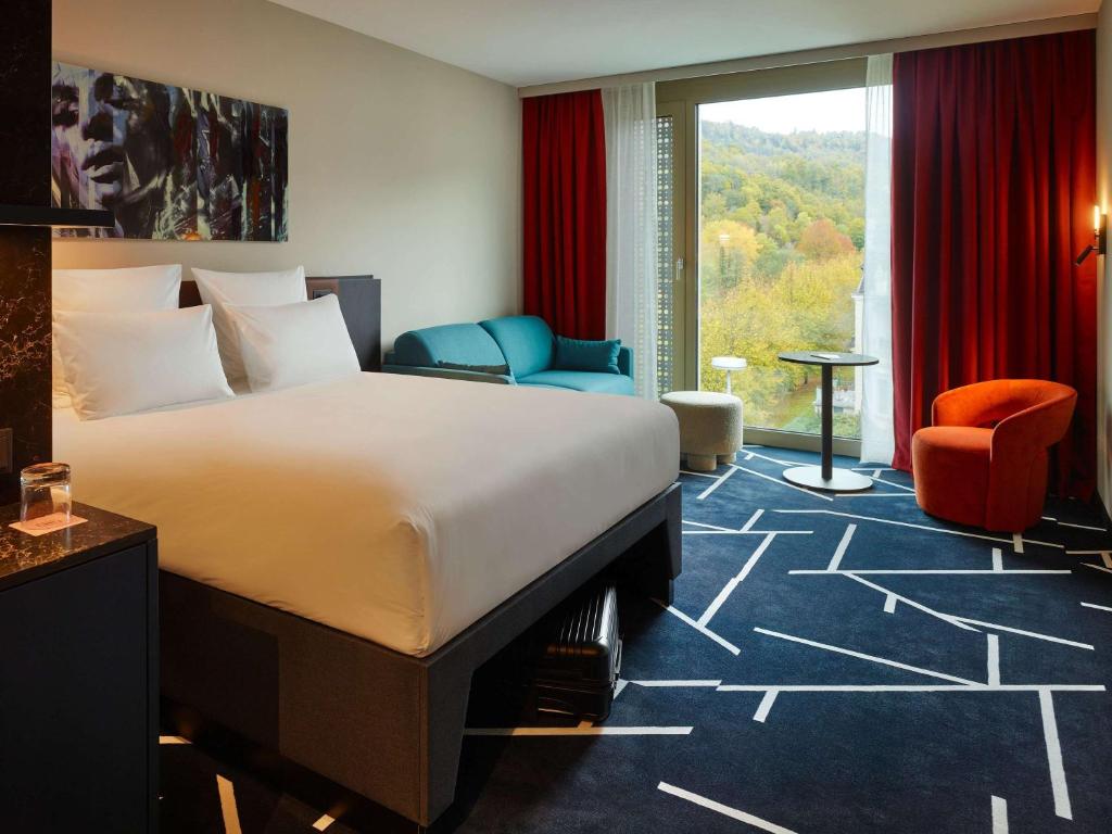 Habitación de hotel con cama, sillas y ventana en TRIBE Baden-Baden, en Baden-Baden