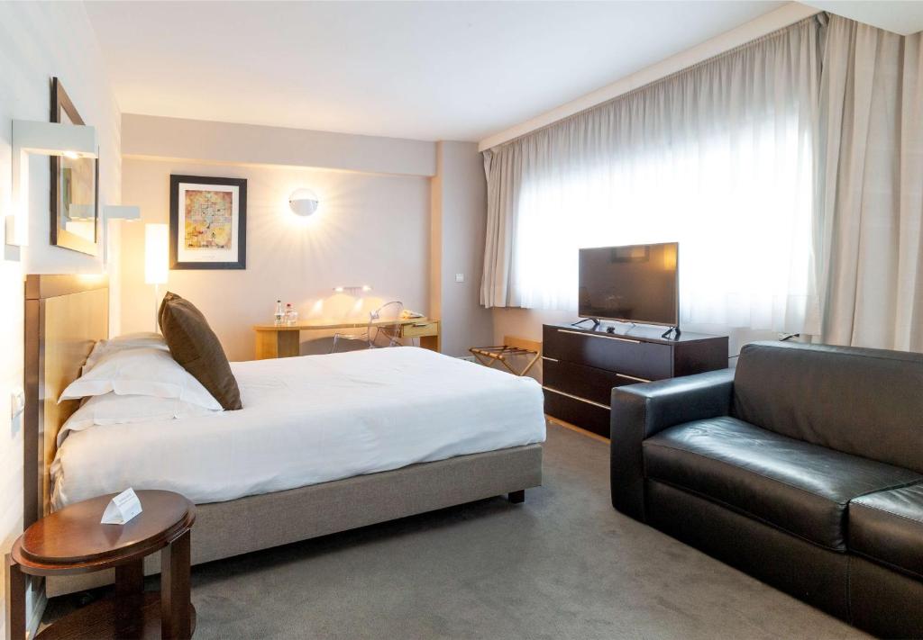 a hotel room with a bed and a couch at Hotel Lille Euralille - Hilton Affiliate Hotel in Lille