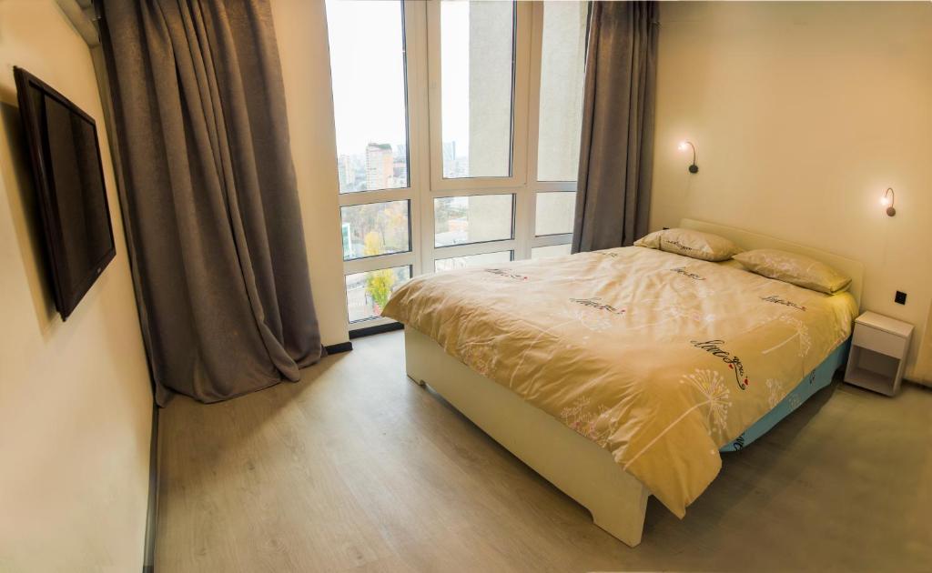 een slaapkamer met een bed en een groot raam bij Апартаменты в новострое рядом с центром in Kiev