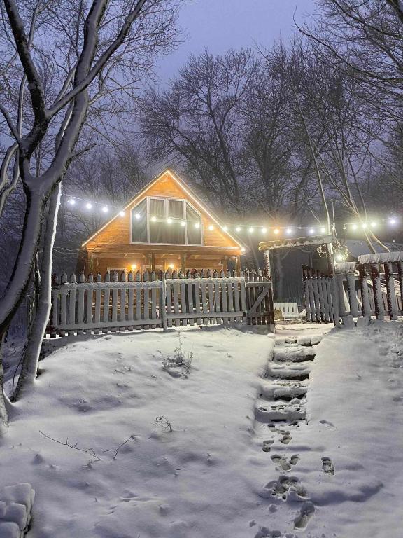 a wooden cabin with a fence in the snow at Wooden House Kopiti in Tbilisi City