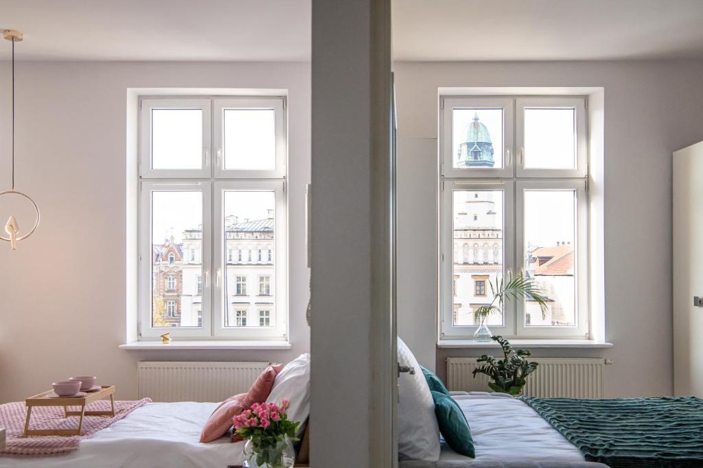 - une chambre avec deux fenêtres et un lit fleuri dans l'établissement Amazing apartament in the heart of Kazimierz, à Cracovie