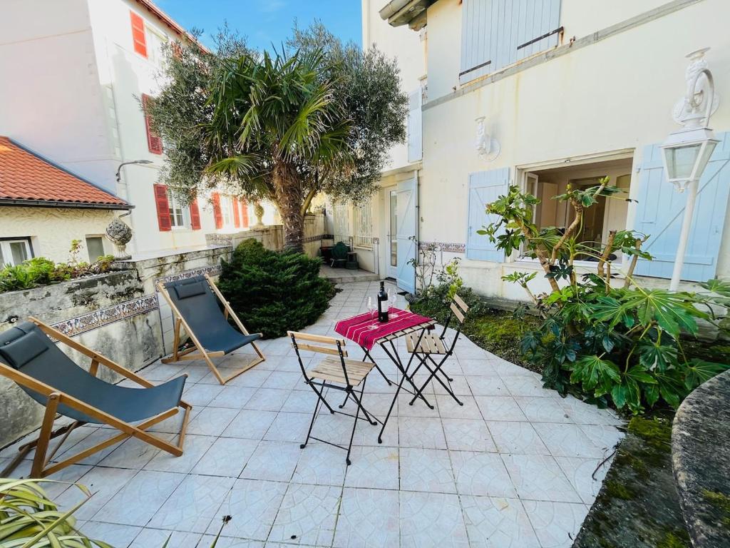 un patio avec une table, des chaises et un palmier dans l'établissement Biarritz hyper centre - Halles - terrasse, à Biarritz