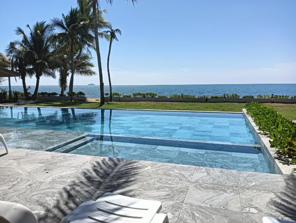 a swimming pool with the ocean in the background at Rayong Chalet Resort in Klaeng