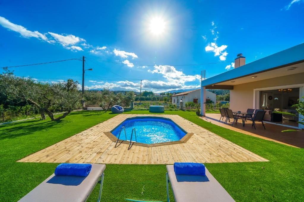 a backyard with a swimming pool and a house at Villa Lima Pool & Jacuzzi Chania in Vamos