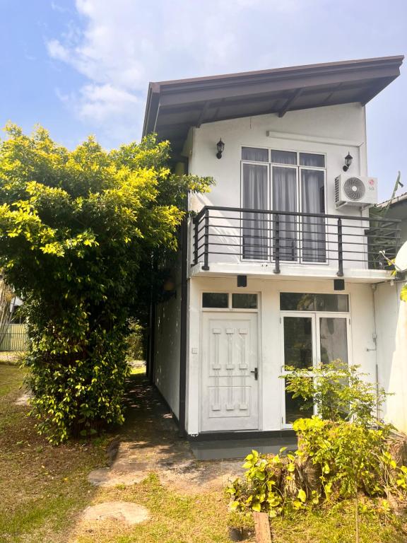 Dieses weiße Haus verfügt über eine Veranda und einen Balkon. in der Unterkunft Elegance Villa in Boralesgamuwa