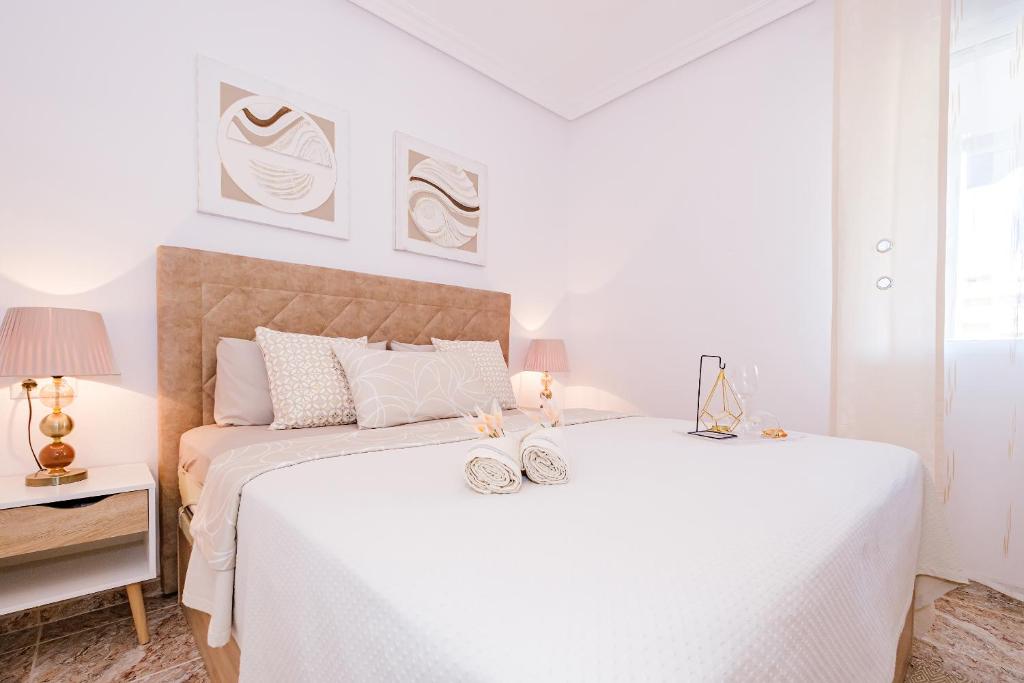 una camera bianca con 2 letti e una lampada di Home&Holiday Goleta with parking-option a Torrevieja