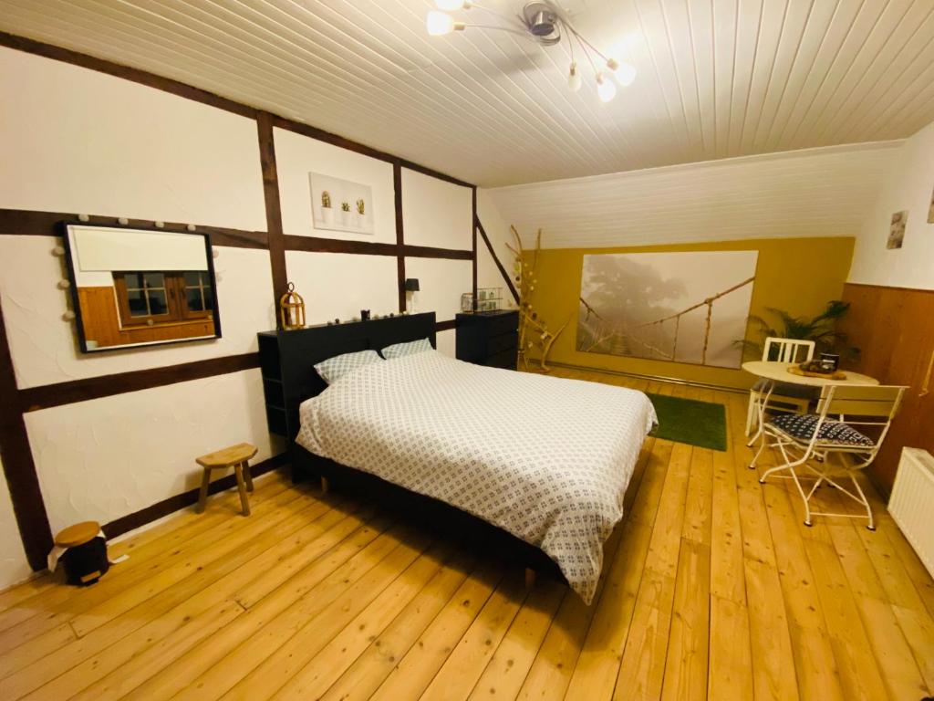sypialnia z łóżkiem i drewnianą podłogą w obiekcie La chambre Cour'toise w mieście Stoumont