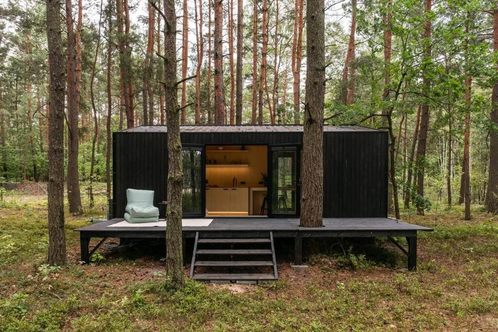 une petite maison noire au milieu d'une forêt dans l'établissement Bento Two, 
