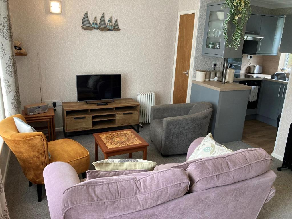 ein Wohnzimmer mit einem lila Sofa und Stühlen in der Unterkunft 35 Siesta Mar in Mundesley