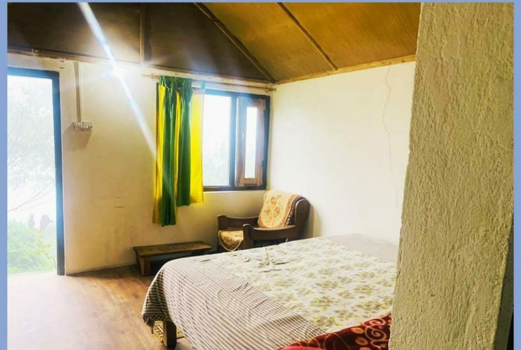 a bedroom with a bed and a chair and a window at Homestay Nature Auli in Joshīmath