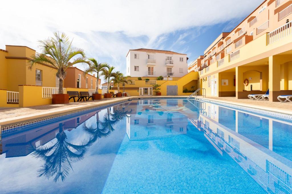 a pool at a hotel with palm trees and buildings at Caletillas Waves & Pool in Candelaria
