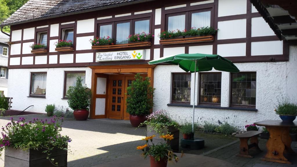 un bâtiment avec un parasol vert devant lui dans l'établissement Gasthof Zwilling, à Schmallenberg