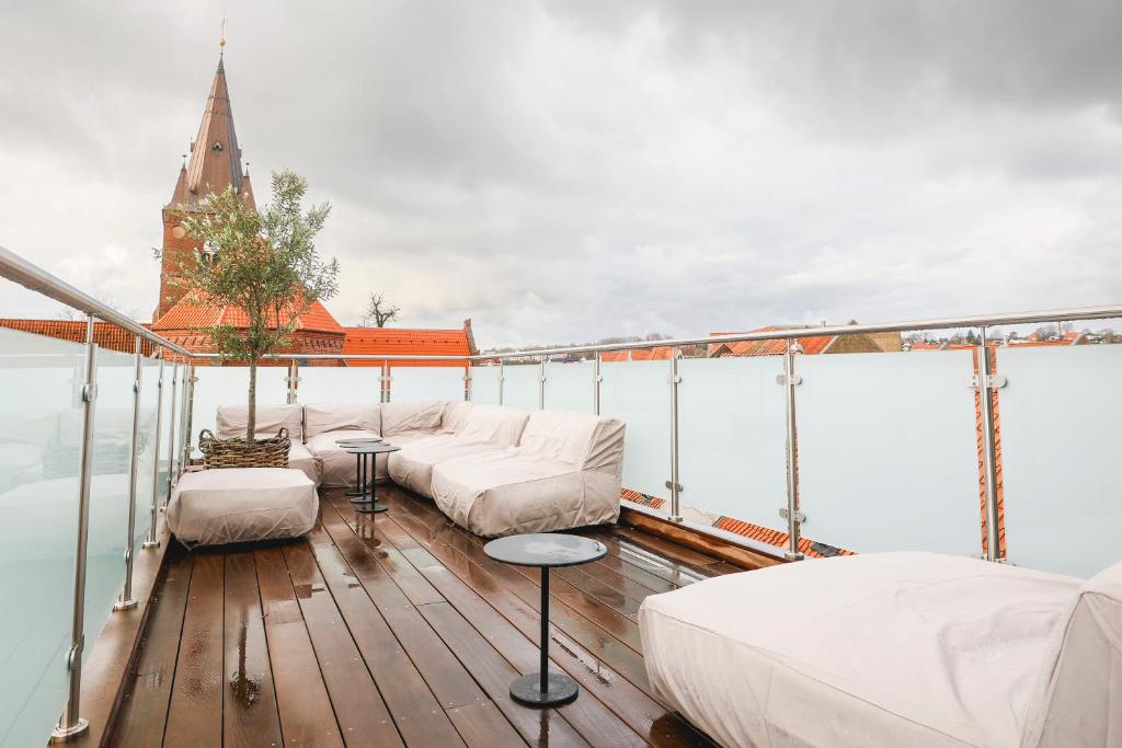 a balcony with white beds and a church at STAY Penthouse in Kolding