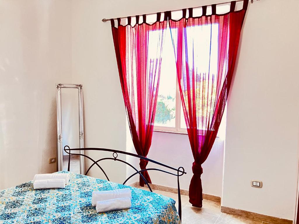 una camera da letto con un letto con tende rosse e una finestra di Newly renovated apartment in the heart of Sorso a Sorso