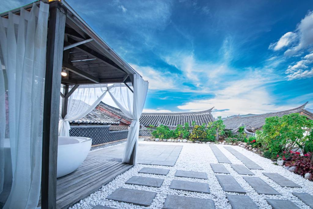 un patio al aire libre con una cortina blanca y un edificio en Lijiang View Holiday Inn, en Lijiang