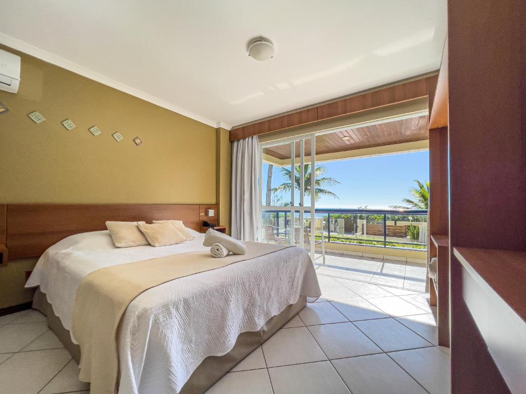 ein Schlafzimmer mit einem Bett und einem großen Fenster in der Unterkunft Pousada Garatéia in Bombinhas