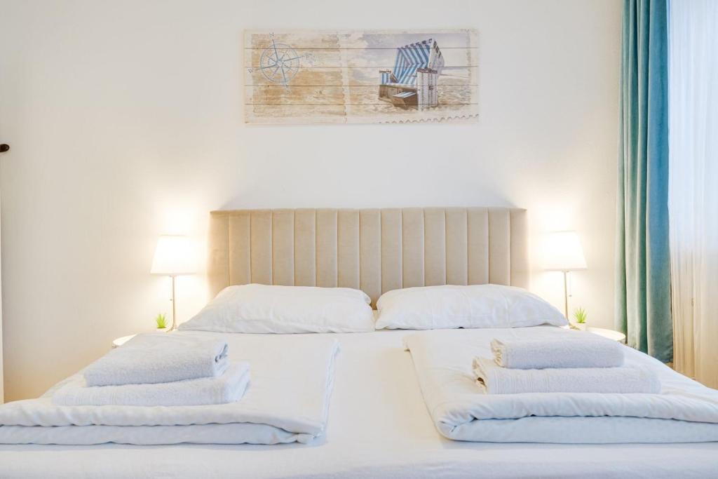 1 dormitorio con 2 camas con sábanas y almohadas blancas en Wohnen auf Zeit - Studiowohnung Innsbruck en Innsbruck