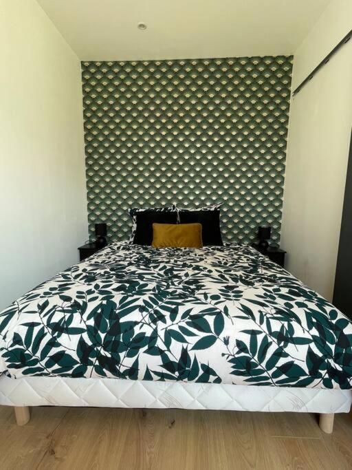 Schlafzimmer mit einem Bett mit einer schwarzen und weißen Bettdecke in der Unterkunft Studio 2 personnes - Bouleries Jump - 24H du Mans in Parence