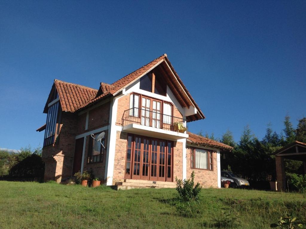 una casa en un campo de hierba con un cielo azul en Cabaña Campestre el Refugio, en Villa de Leyva