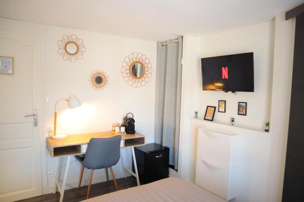 Habitación con escritorio, silla y TV. en Le Moment Douillet, en Bourbourg