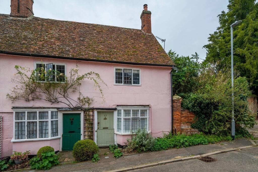 ein rosa Haus mit einer grünen Tür auf einer Straße in der Unterkunft Dragonfly Cottage, Long Melford in Long Melford
