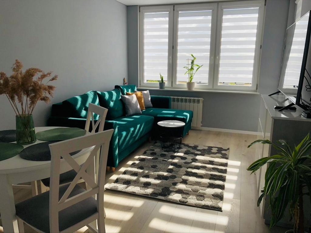 a living room with a green couch and a table at Apartament Panorama miasta in Olsztyn