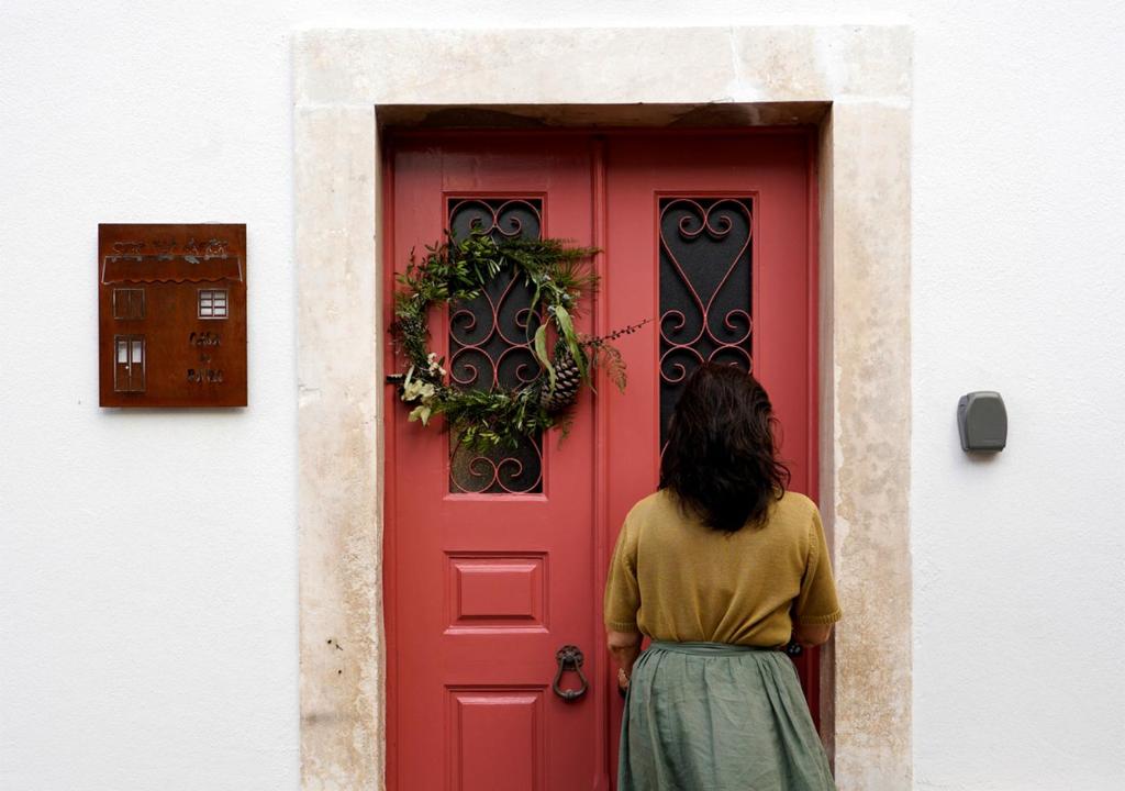 a woman standing in front of a red door at Casa do Pátio, casaspensadas in Juncal