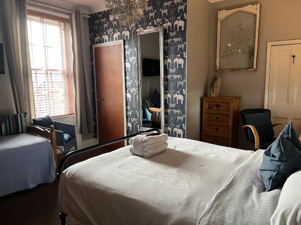 a bedroom with a large white bed with blue and white wallpaper at Kelston Guest House in Weymouth