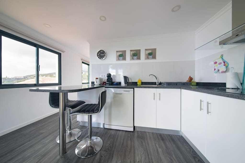 eine Küche mit weißen Schränken und einem Tisch mit Stühlen in der Unterkunft Lombo do Doutor Cottage 1 by Mth in Calheta