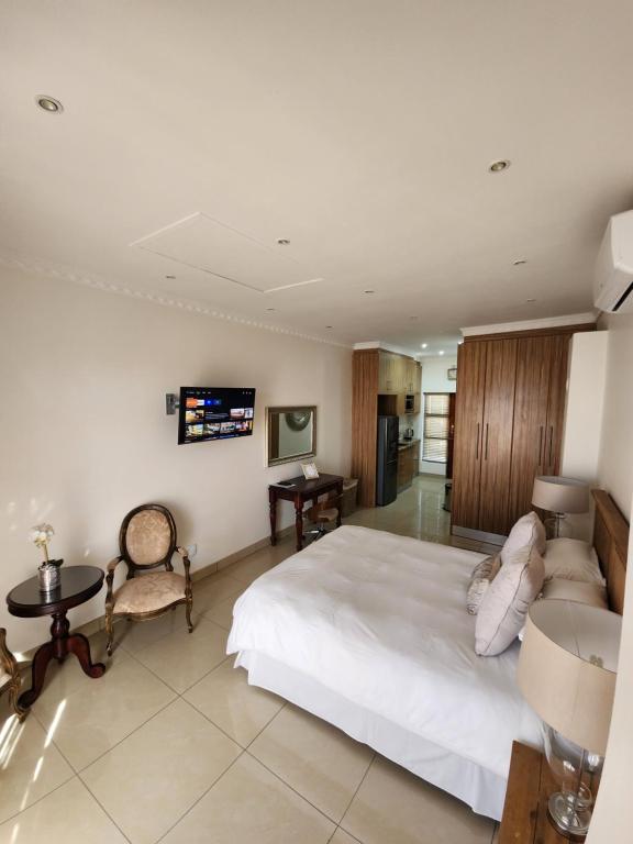 a bedroom with a white bed and a tv on the wall at Villa Marche in Van Riebeekhoogte