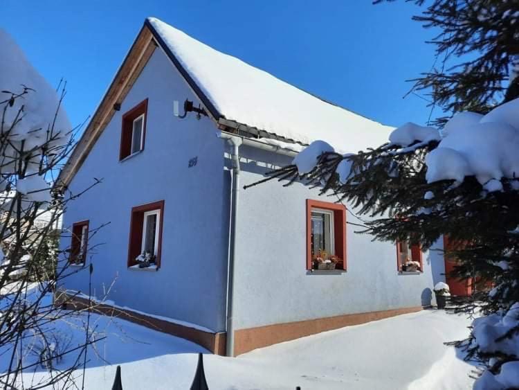 uma casa branca com neve no telhado em Chalupa Amálka em Zaclér