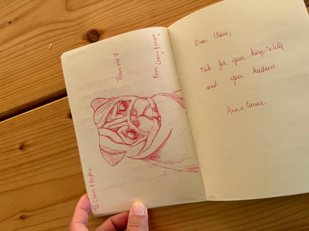 a person holding a book with a drawing of a dog at Cute Pug Guest Room in Copenhagen