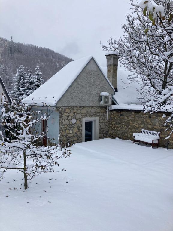una casa cubierta de nieve con un banco en Ludvov Dom, en Tajov