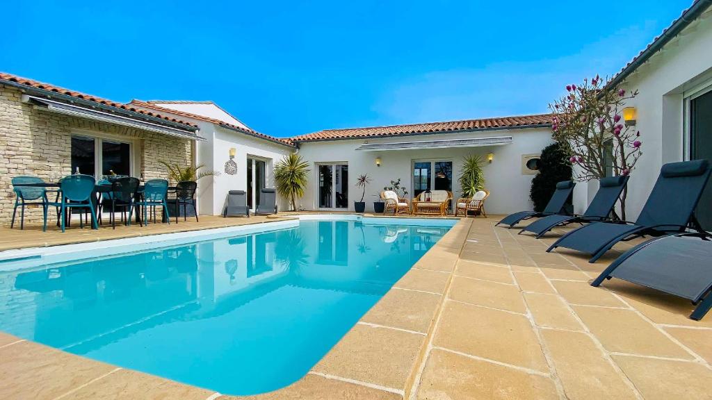 a swimming pool with chairs and a house at Magnifique villa avec piscine et billard in Saint-Martin-de-Ré