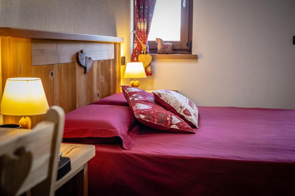 1 dormitorio con 1 cama con sábanas y almohadas rojas en Le Coin des Mélèzes - NATURE & TREK en Brusson