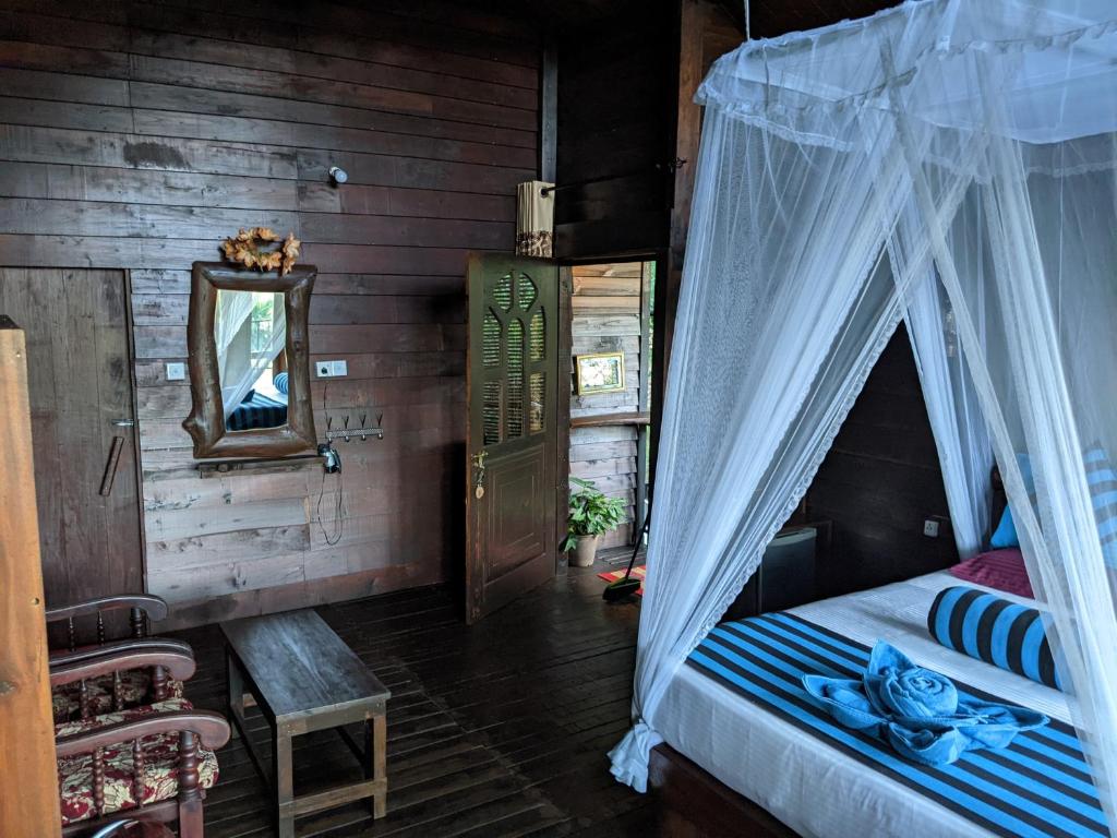 a bedroom with a bed with a canopy at Madushanka Resort in Ella