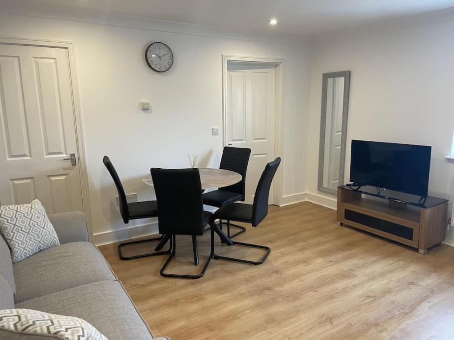 uma sala de estar com uma mesa e cadeiras e uma televisão em Modern The Mews Apartment em Bury Saint Edmunds