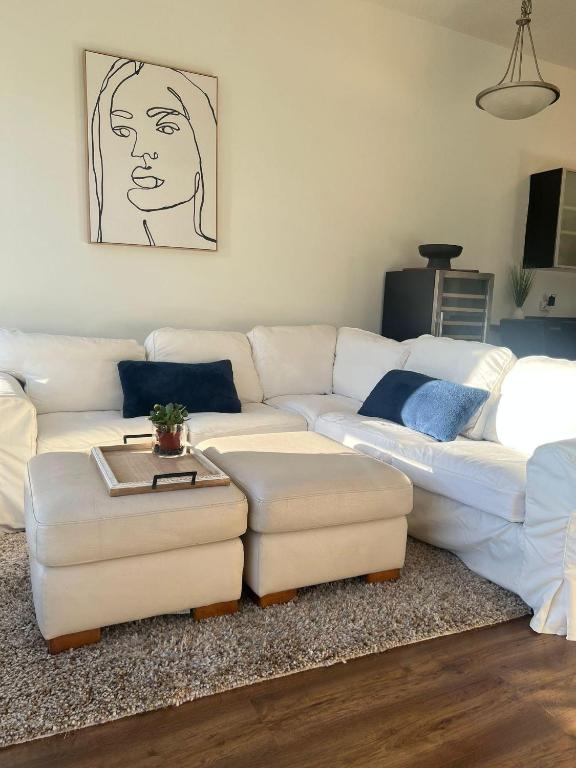a living room with a white couch and two ottoman at Laid Back In Langford in Langford