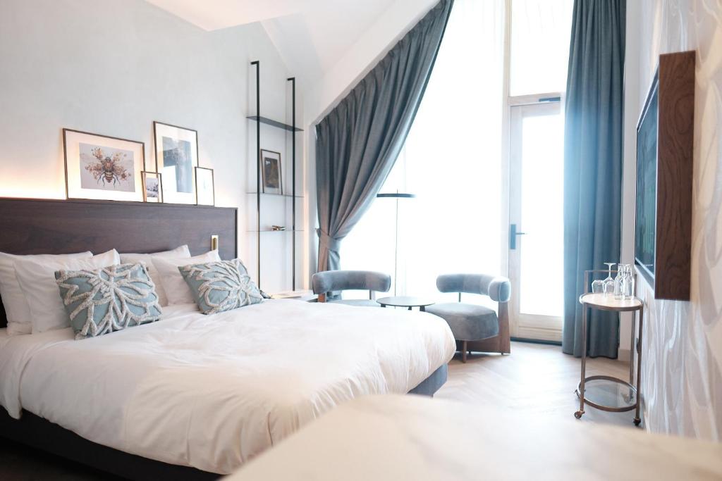 1 dormitorio con 1 cama grande y cortinas azules en Boutique Hotel Blendin Bloemendaal aan Zee, en Overveen